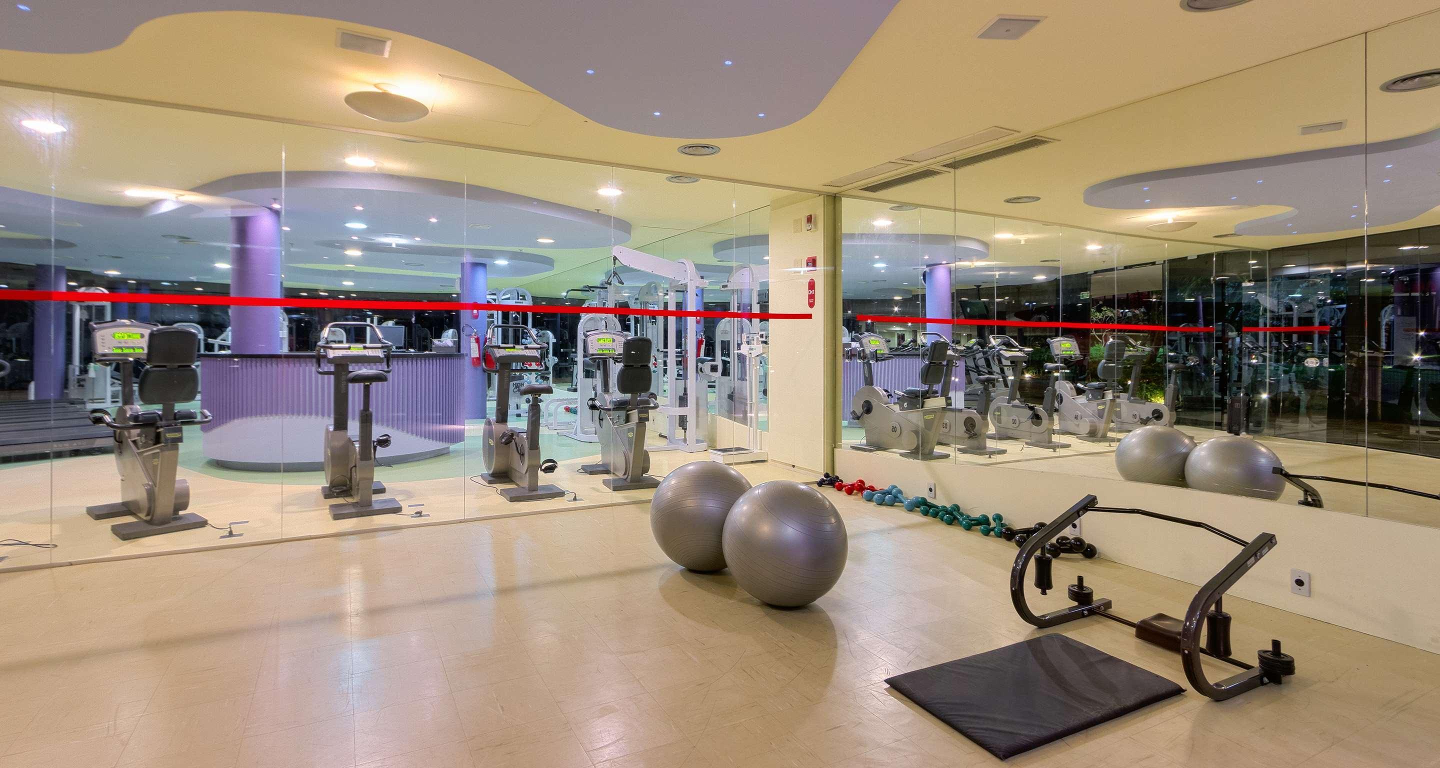 Hotel Royal Tulip Brasilia Alvorada Exterior foto The photo depicts a gym or fitness area. In the foreground, there are two large exercise balls and a mat on the floor. Behind them, there is a wall of mirrors that reflects various gym equipment, including exercise machines and bikes. The lighting in